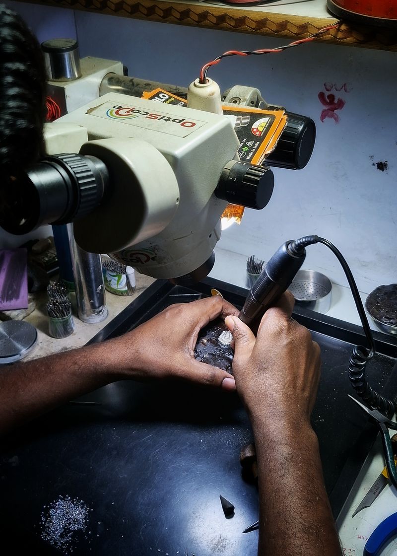 Craftsman setting a stone under a microscope at our Kolkata jewellery workshop